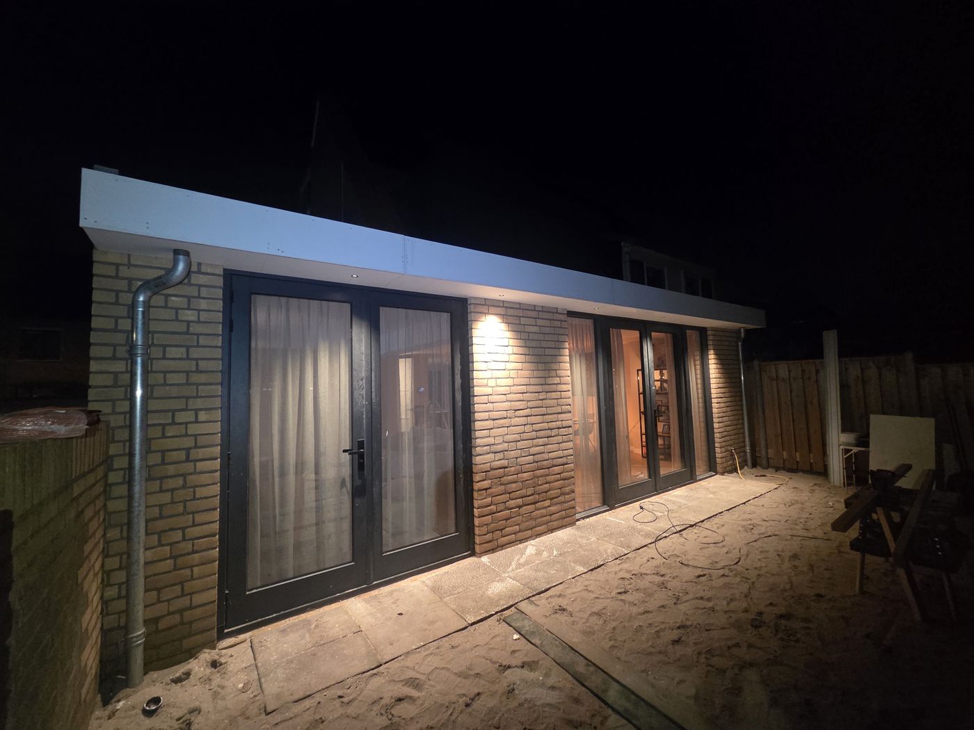 Nieuwe aanbouw met openslaande deuren en buitenverlichting