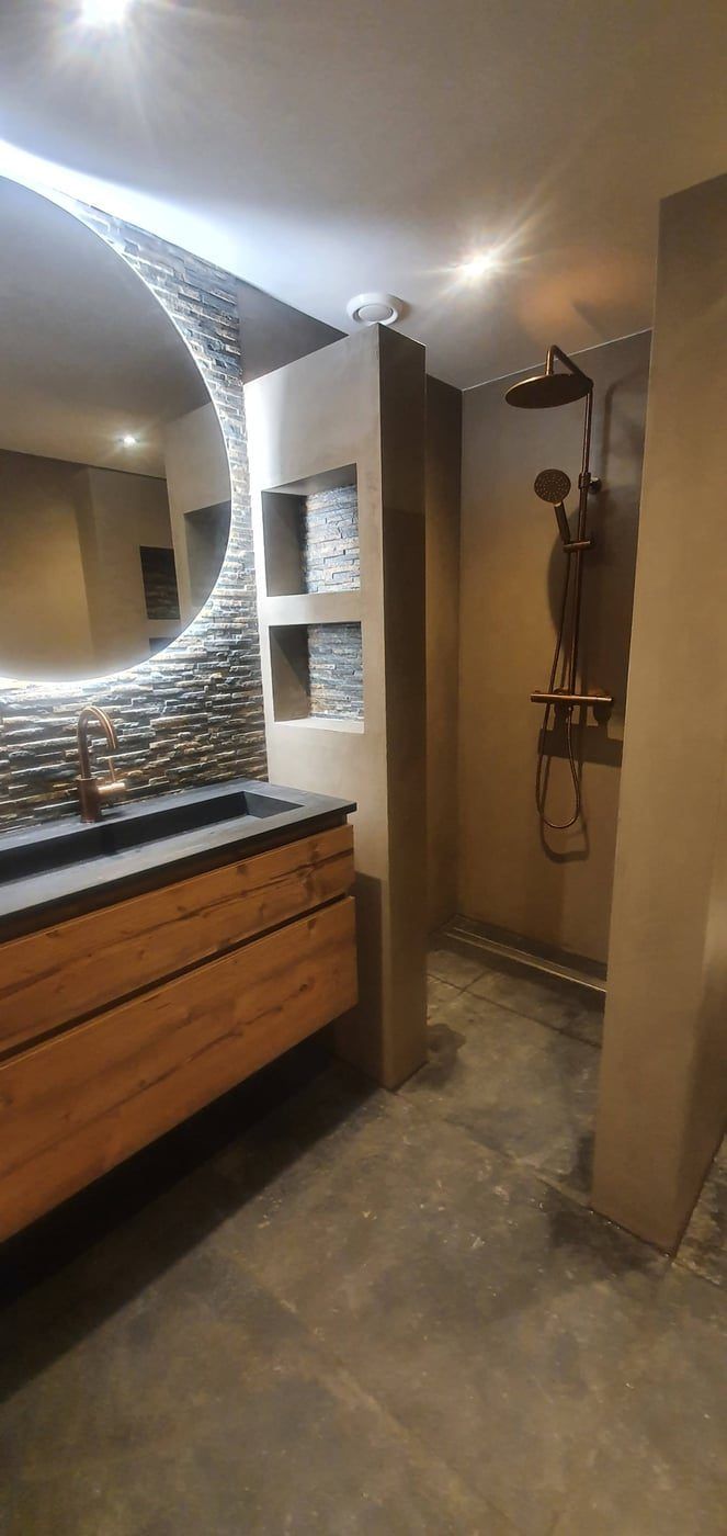 Badkamer met ronde verlichte spiegel, eiken badmeubel en inloopdouche