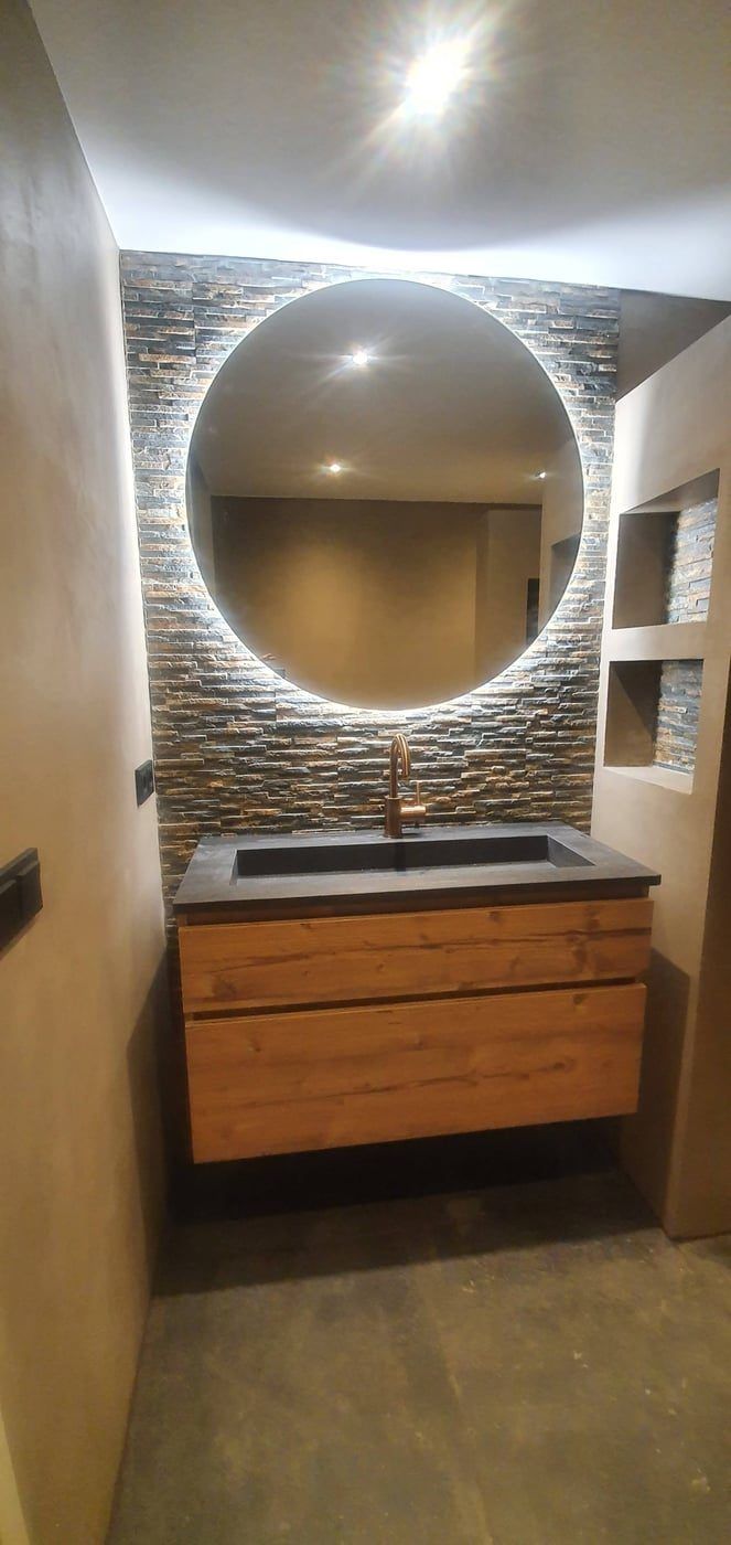 Wastafelwand met ronde spiegel, natuursteen strips en eiken onderkast