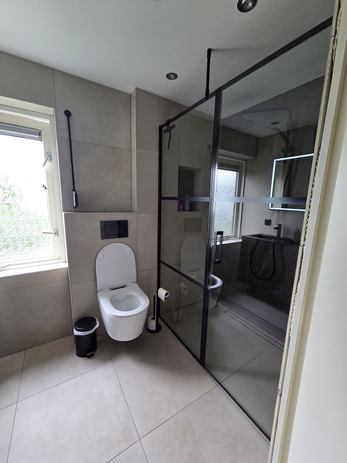 Badkamer met zwarte inloopdouche en hangtoilet
