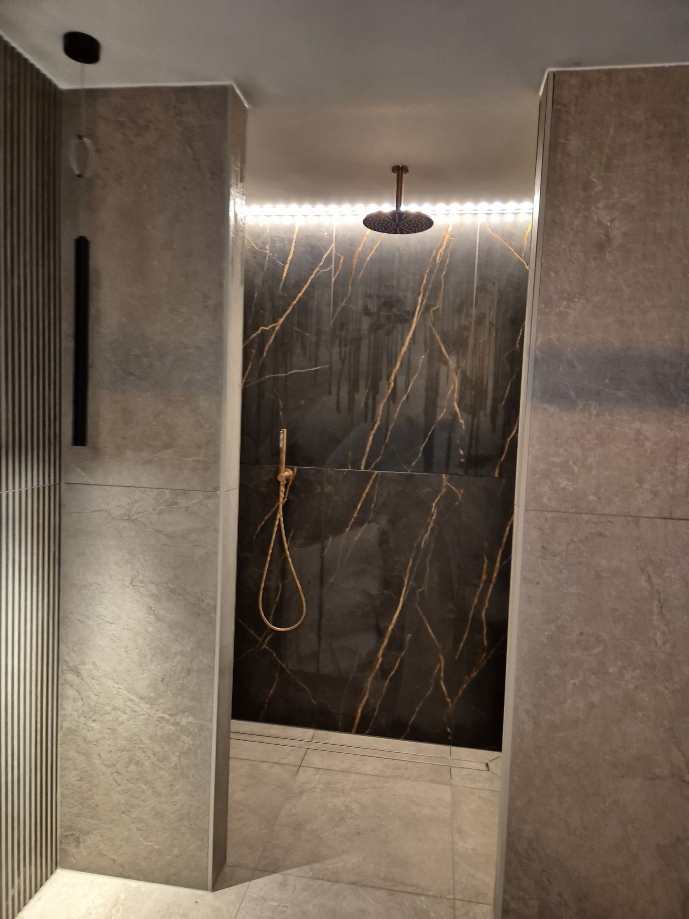 Inloopdouche met marmerlook tegels, gouden kranen en LED-verlichting