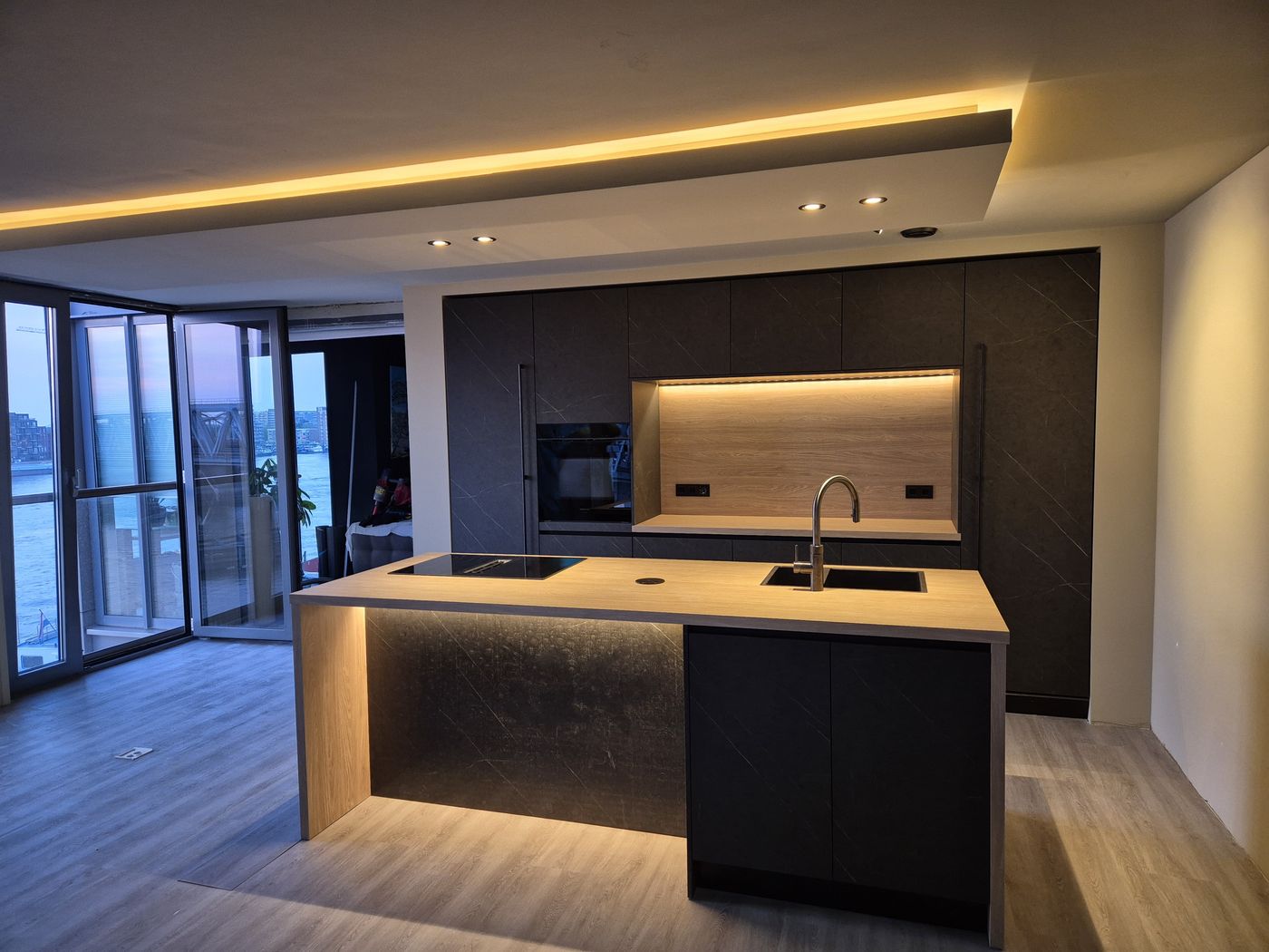 Donkere keuken met eiken kookeiland en verlaagd plafond met LED-verlichting