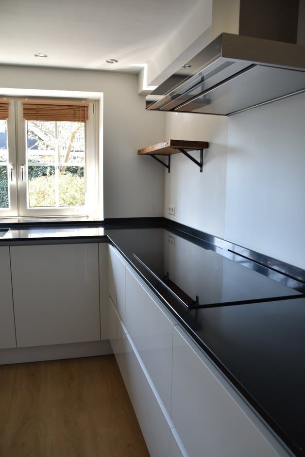 Witte keuken met zwart werkblad en wandplanken