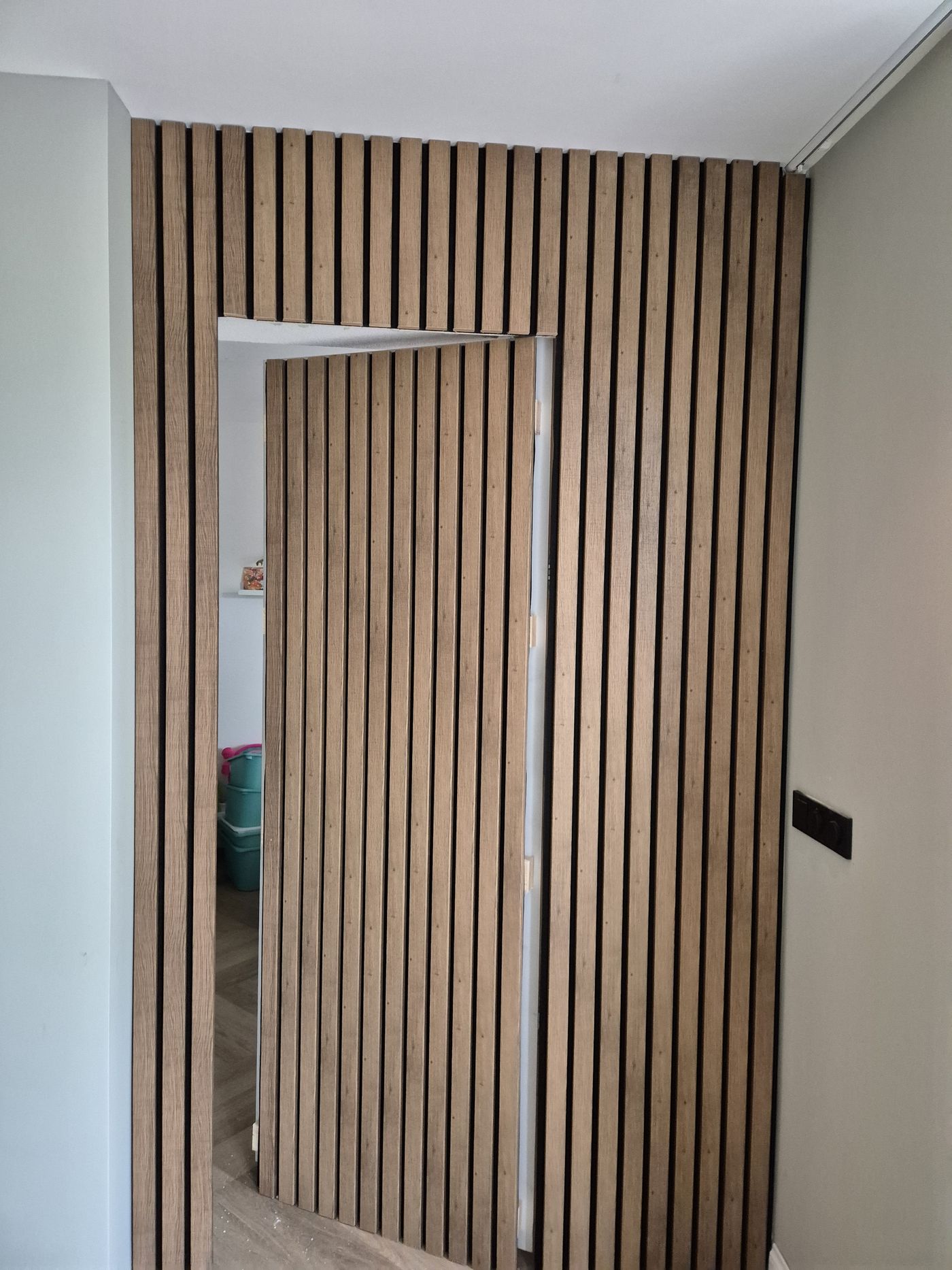 Akoestische lamellenwand met verborgen deur