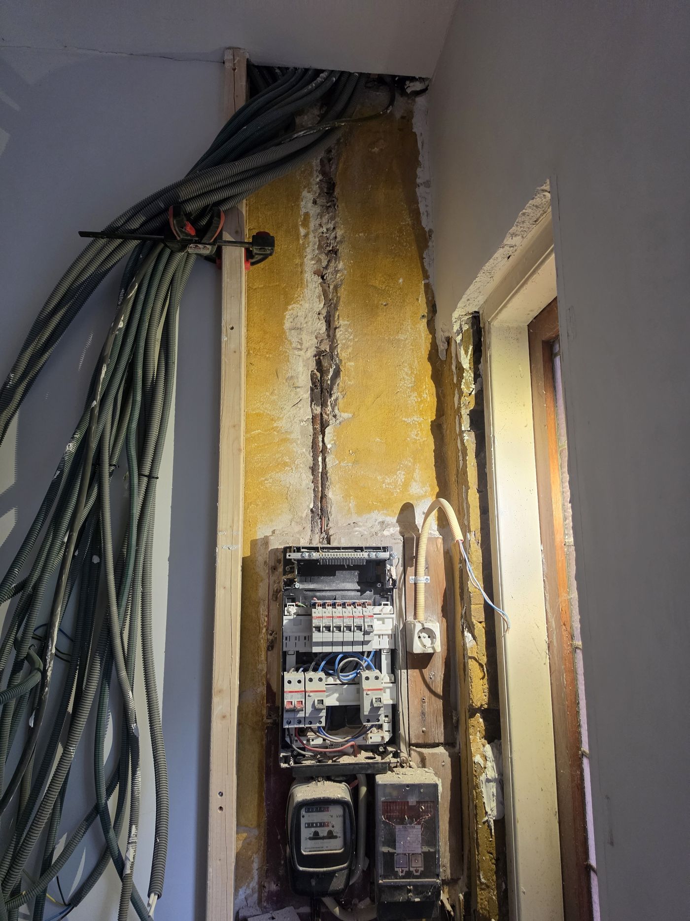 Verouderde meterkast met losse kabels voor de renovatie