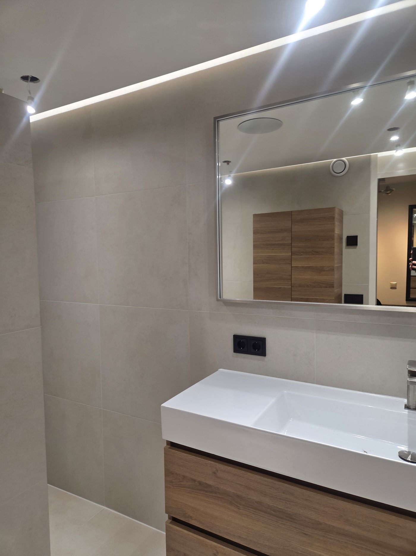 Wastafel met houten kast onder een LED-plafond